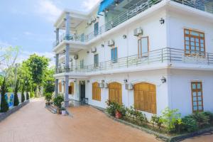a white building with yellow doors and a brick road at Sơn Lâm Hotel in Chợ Hiếu +16 photos