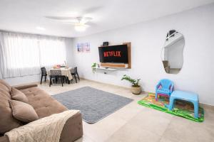 a living room with a couch and a television at Casa do Sol - 300M da Praia - Ar condicionado in São Pedro da Aldeia