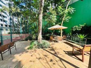 a patio with benches and an umbrella and a tree at Blu Flat Prime Verbo Divino in São Paulo