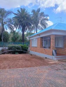 a brick house with palm trees in the background at Moonlight Guest House in Johannesburg