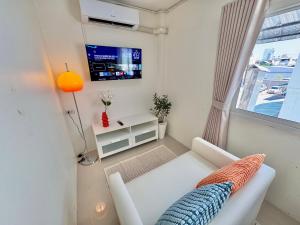 a living room with a white couch and a tv at Boon Poshtel Hatyai in Sathani Hat Yai