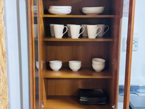 a wooden shelf with cups and plates on it at ゲストハウス元町 in Ise +28 photos