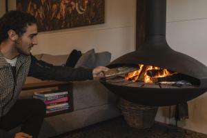 a man putting a pizza into a fire oven at Old Bales Serene Hinterland Oasis in Myocum