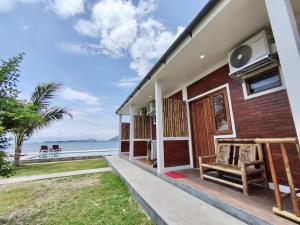 a house on the beach with a bench on the porch at Alden Beach House in Sekotong