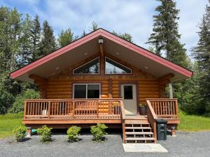 a log cabin with a large deck and a porch at Clear Creek Cabins in Seward