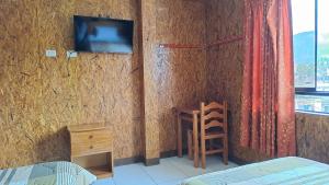 a room with a wall with a tv and a desk at Hospedaje El Manantial in Chontabamba