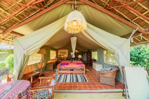 a tent with a bed and a chandelier at Buffalo's Rest Greenpark-Naivasha in Naivasha