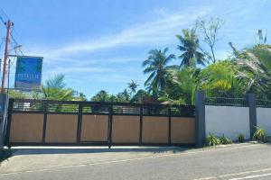 a gate on the side of a road with palm trees at Estellie Resthouse in Maya +4 photos