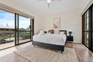 a bedroom with a bed and large windows at Beachfront - Opposite Boat Ramp in Golden Beach +7 photos