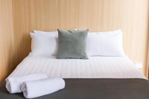 a bed with white pillows and two towels on it at Saddle House by Tiny Away in Lower Beechmont