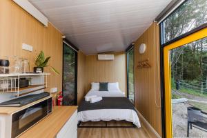 a bedroom in a tiny house with a bed at Saddle House by Tiny Away in Lower Beechmont