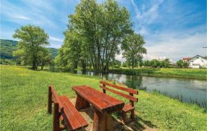 a wooden bench sitting in the grass next to a river at Beautiful Home In Otocac in Otočac