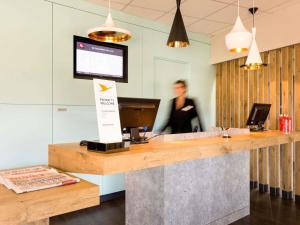 a woman standing behind a reception desk in a office at ibis Carcassonne Est la Cité in Carcassonne +96 photos