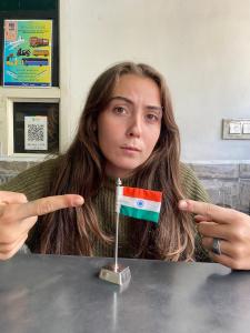 a woman is pointing at a small flag on a table at Flamingos Hostel Jaipur in Jaipur