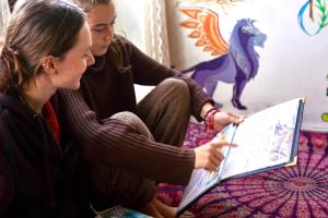 two women sitting on a bed looking at a laptop at Flamingos Hostel Jaipur in Jaipur