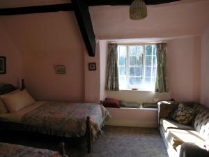 a bedroom with a bed and a window with a couch at West Wing- Ukc4914 in Timberscombe