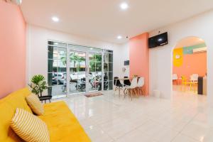 a living room with a yellow couch and tables and chairs at Sans Hotel Cengkareng in Jakarta