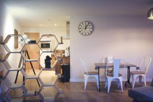 Un comedor con una mesa y sillas y un reloj. en Homely Serviced Apartments - Blonk St, en Sheffield