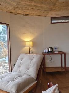 a couch in a room with a table and a lamp at The Garhwal Huts in Pauri