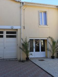 una casa con puertas blancas de garaje y dos palmeras en Le Preia, en Prez-sur-Marne