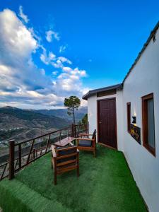 a balcony with chairs and a view of the mountains at The Garhwal Huts in Pauri