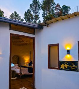 a white house with a room with a bed at The Garhwal Huts in Pauri +2 photos