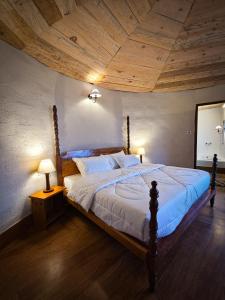 a bedroom with a large bed with a wooden ceiling at The Garhwal Huts in Pauri