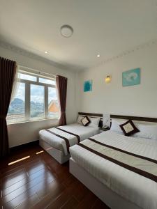 a bedroom with two beds and a window at Tommy hotel khe sanh dalat in Da Lat