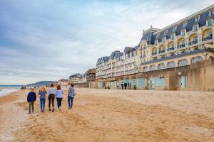 a group of people walking on the beach at Maison avec jardin, calme et ensoleillée à 2 minutes du centre-ville in Cabourg