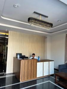 a man standing behind a counter in a lobby at Bhavya Guest House in Rīngas