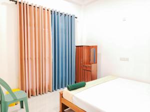 a bedroom with curtains and a bed and a chair at NRS Villa Midigama in Midigama East