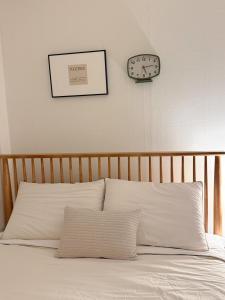 a bed with white pillows and a clock on the wall at juns house in Ulsan