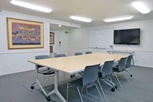 a conference room with a table and chairs and a screen at Ramada Plaza by Wyndham Waikiki in Honolulu +46 photos