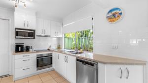a kitchen with white cabinets and a sink at Coastal Palms Hideaway in Bongaree +16 photos