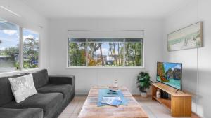 a living room with a couch and a table at Coastal Palms Hideaway in Bongaree