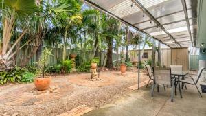 a patio with a table and chairs and palm trees at Coastal Palms Hideaway in Bongaree