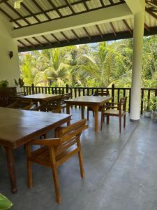 a restaurant with wooden tables and chairs and palm trees at Lila Lodge, Villa - Bentota in Bentota