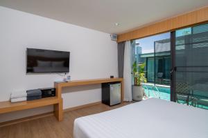 ein Schlafzimmer mit Bett, Fernseher und Balkon in der Unterkunft Xen Pool Access Phuket in Chalong 