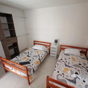 a bedroom with two beds and a night stand at Apartamentos Las Orquideas in San Pedro