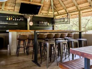 a bar with stools and a flat screen tv at Syeta Bush Lodge - Luxury Bush Villa in Crocodile Valley Estates