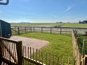 a wooden fence next to a grassy field at Haus im Halligweg 20 in Nordstrand +14 photos