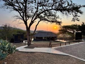 a tree and a building with the sunset in the background at Syeta Bush Lodge - Bush Serenity in Nelspruit +11 photos