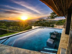 a swimming pool with a sunset in the background at Syeta Bush Lodge - Sunset View in Nelspruit