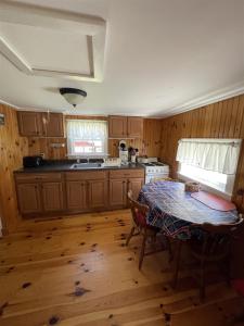 a kitchen with wooden cabinets and a table in it at THE SHOPPE LIMIT 3 cabin in North Sebago