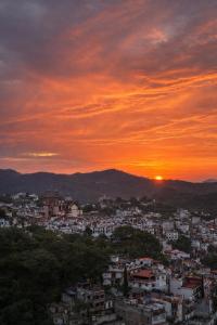 a view of a city with a sunset in the background at Entre el sol y la luna in Taxco de Alarcón +6 photos