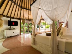 a bedroom with a bed with curtains and a tv at Biu Biu Resort Bali in Jimbaran