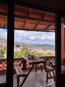 a table and benches on a balcony with a view at Entre el sol y la luna in Taxco de Alarcón