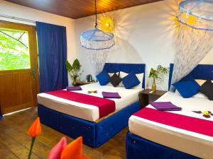 a bedroom with two beds with blue and red sheets at Nature Rest Ashored in Sigiriya
