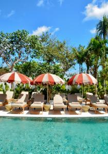 a group of chairs and umbrellas next to a swimming pool at The Balangan Hotel Uluwatu - 2min to Beach & 5min to Bali's Best Golf in Uluwatu