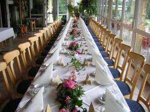 a long table with white plates and flowers on it at Hotel am Lärchenberg in Schirgiswalde